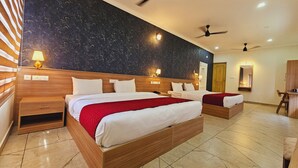 A hotel room with two beds, wooden headboards, marble flooring, ceiling fans, and wall-mounted lights. - ESAA Airport Hotel (Aluva)