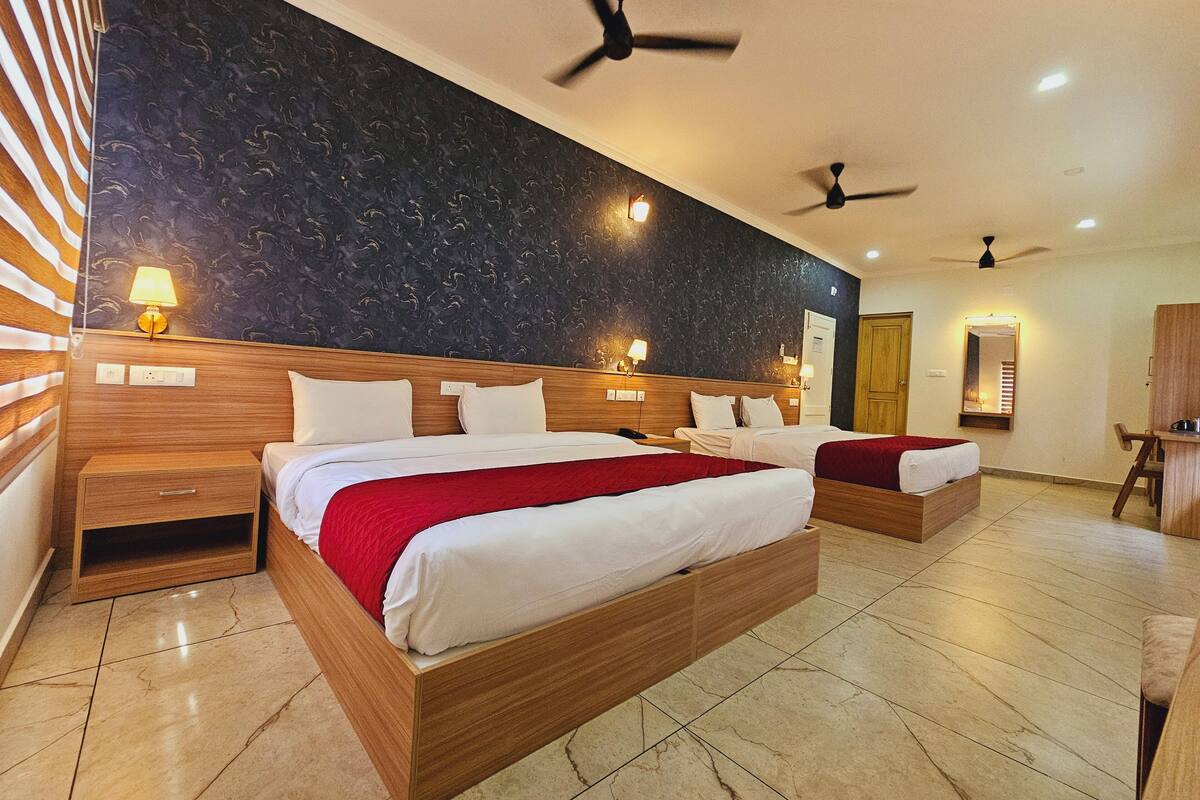 Une chambre d’hôtel avec deux lits, des têtes de lit en bois, un revêtement de sol en marbre, des ventilateurs de plafond et des lampes fixées au mur.
