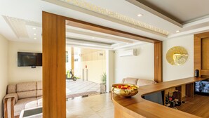 A modern reception area with a wooden reception desk, a sofa, and a television mounted on the wall. - ESAA Airport Hotel (Aluva)
