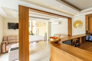 A modern reception area with a wooden reception desk, a sofa, and a television mounted on the wall.