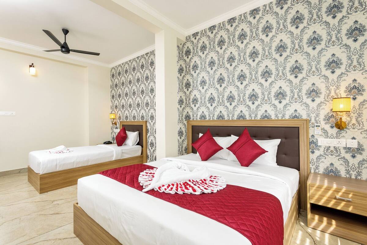 Une chambre d’hôtel avec deux lits, un ventilateur de plafond, un papier peint à motifs et des lampes de chevet.
