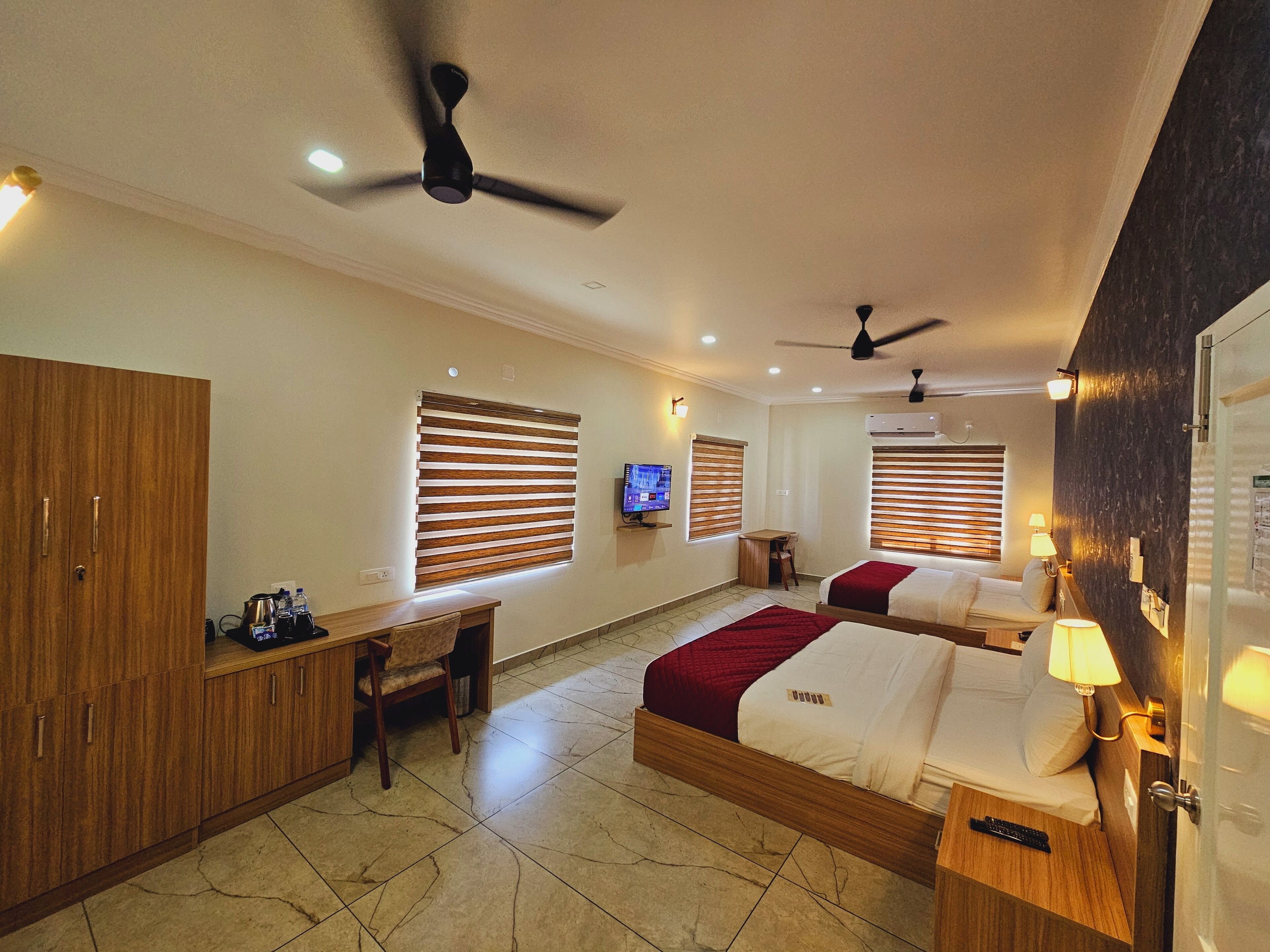 A hotel room with two beds, a desk, and a TV.