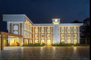 A multi-story hotel with a central entrance, illuminated windows, and a sign reading "ESAA".
