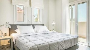 Une chambre à coucher avec un lit, une table de chevet, une lampe et une fenêtre avec des rideaux.