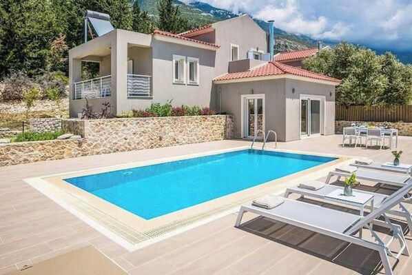 Une maison moderne dotée d’une piscine, de mobilier d’extérieur et d’un mur en pierre.