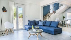 Un salon moderne avec un canapé bleu, une table basse ronde et un escalier menant à un niveau supérieur.