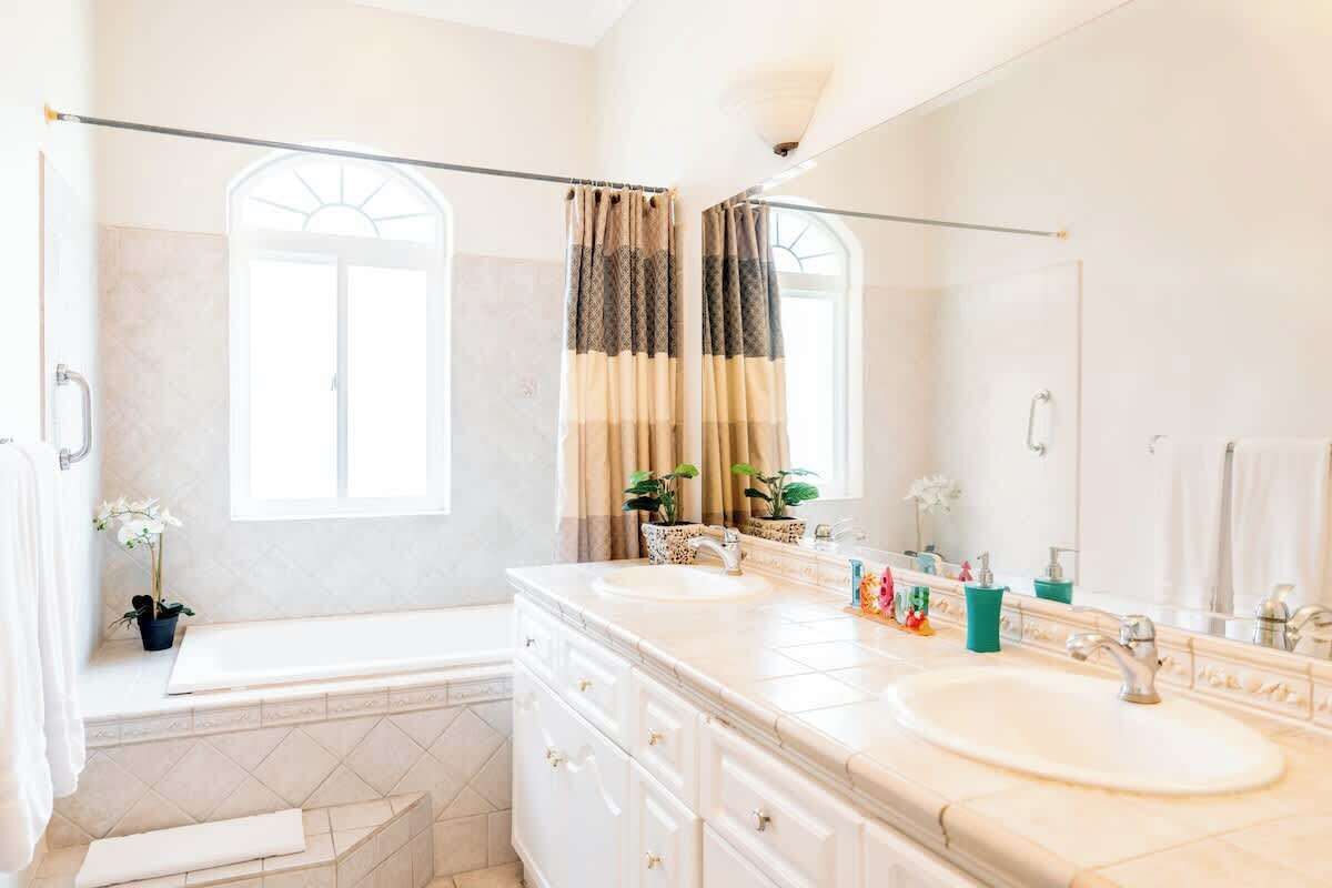 Une salle de bain avec deux lavabos, une baignoire, une douche et un grand miroir.