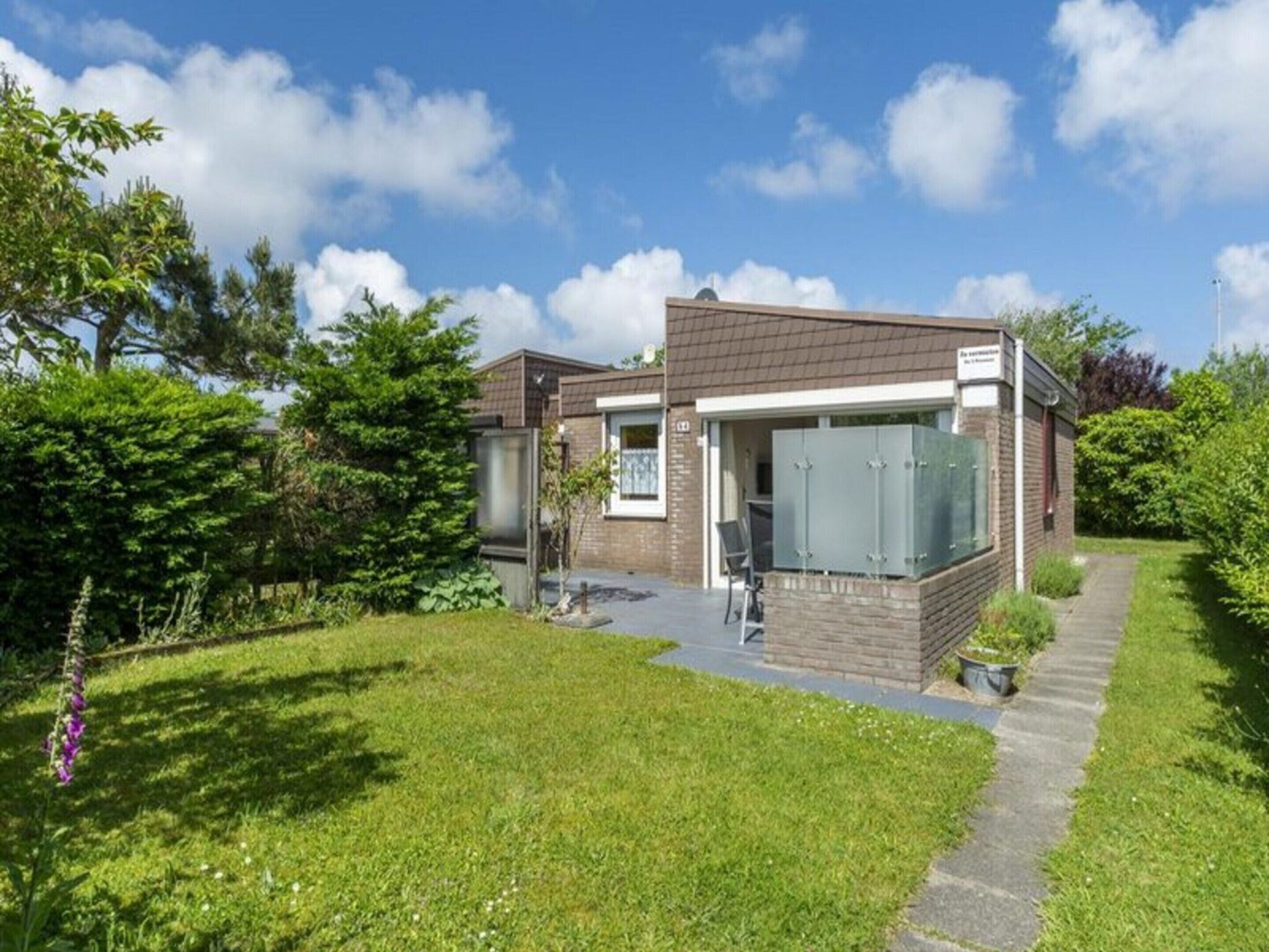 A modern house with a brick exterior, a large glass window, and a paved driveway.