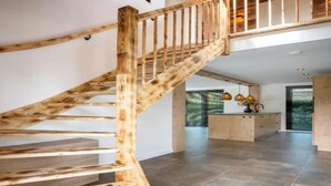 A spacious interior with a wooden staircase leading to an upper level. - a Nice Holiday by the sea With Family (Julianadorp)