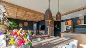 A modern dining area with a wooden table, chairs, and hanging pendant lights. - a Nice Holiday by the sea With Family (Julianadorp)