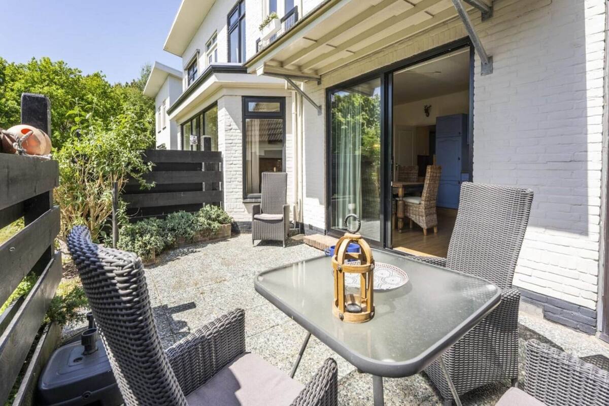 An outdoor patio with wicker furniture, a table, and a lantern.