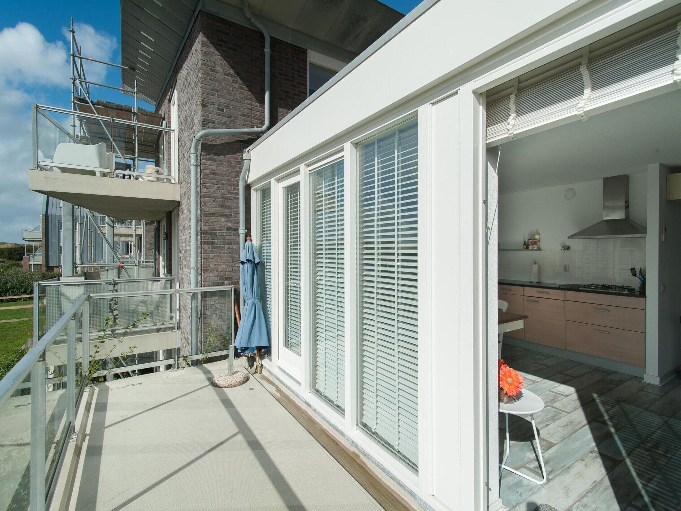 A modern residential building with a balcony, a kitchen with a gas stove, and a chimney.