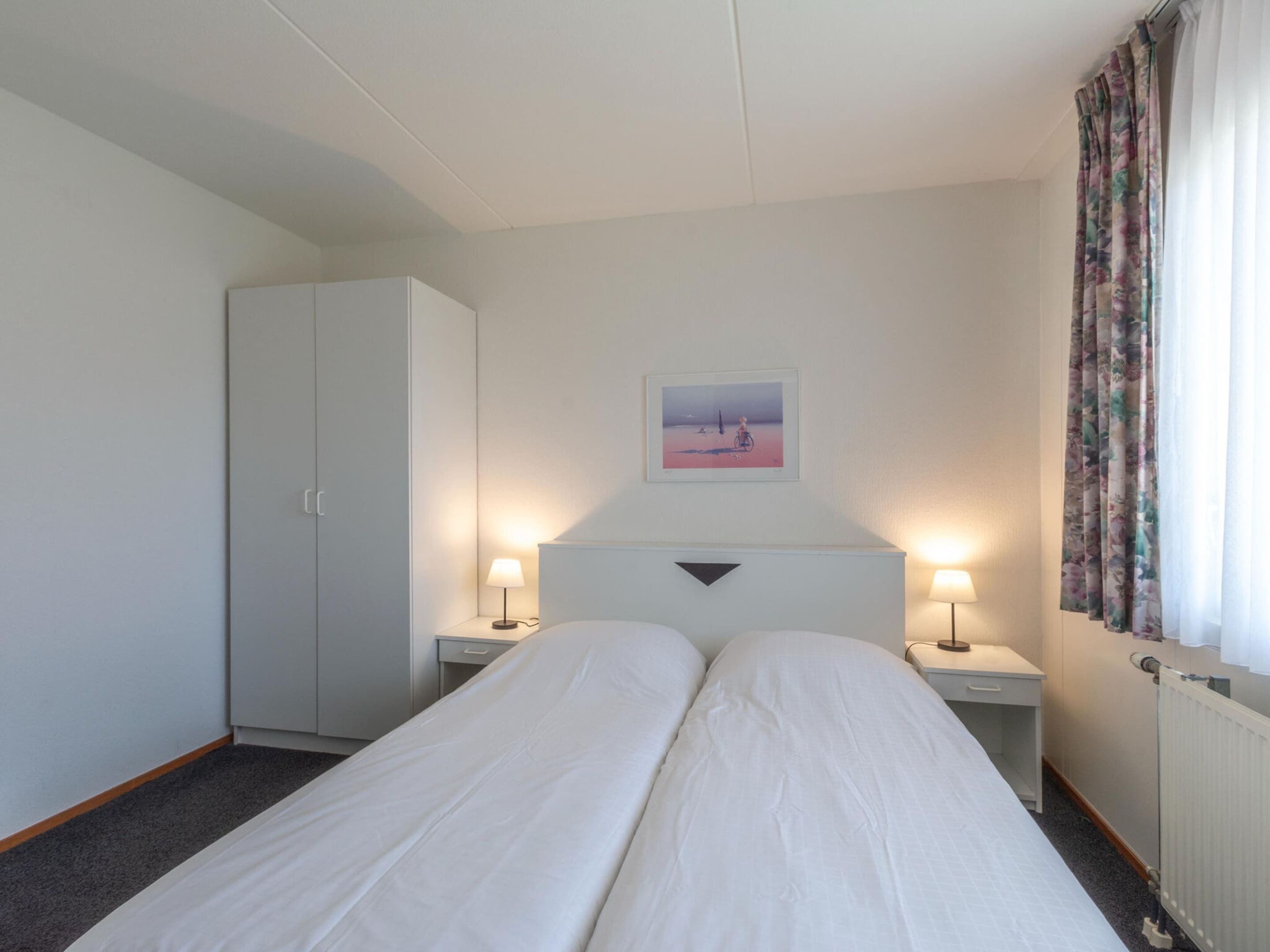 A twin room with two single beds, a wardrobe, a desk, and a radiator.