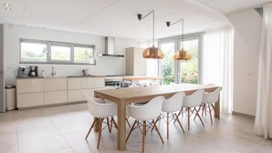 Una cocina moderna con una isla grande, armarios blancos e iluminación colgante.