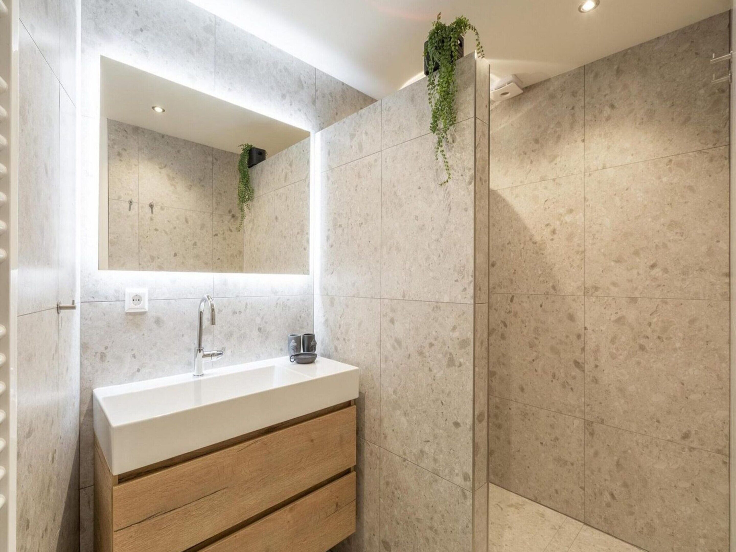 Une salle de bain moderne avec un meuble-lavabo blanc, un miroir et un espace douche.