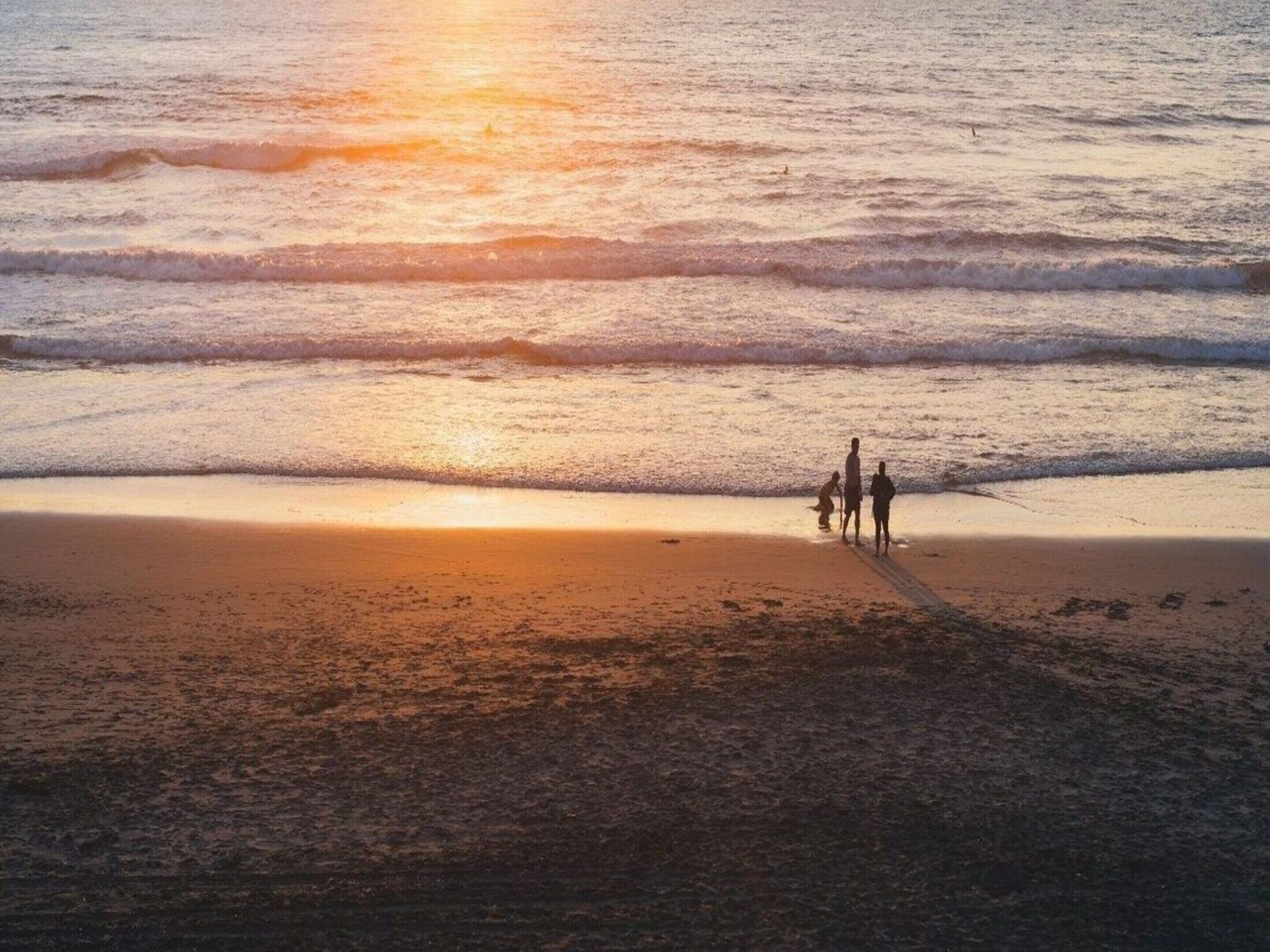 A beach scene with waves and a sunset.