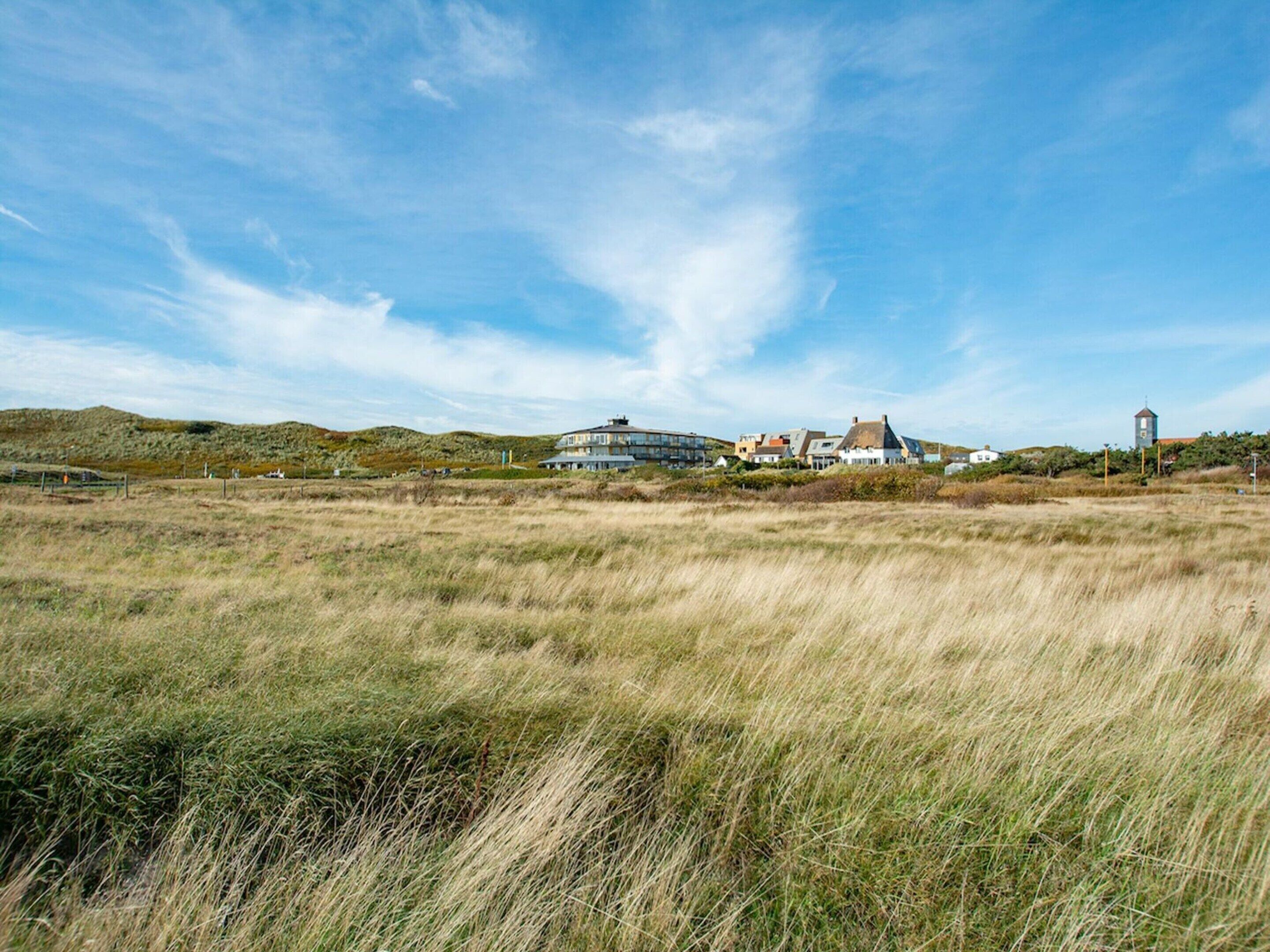 A coastal landscape with a large building featuring multiple levels and a prominent tower.