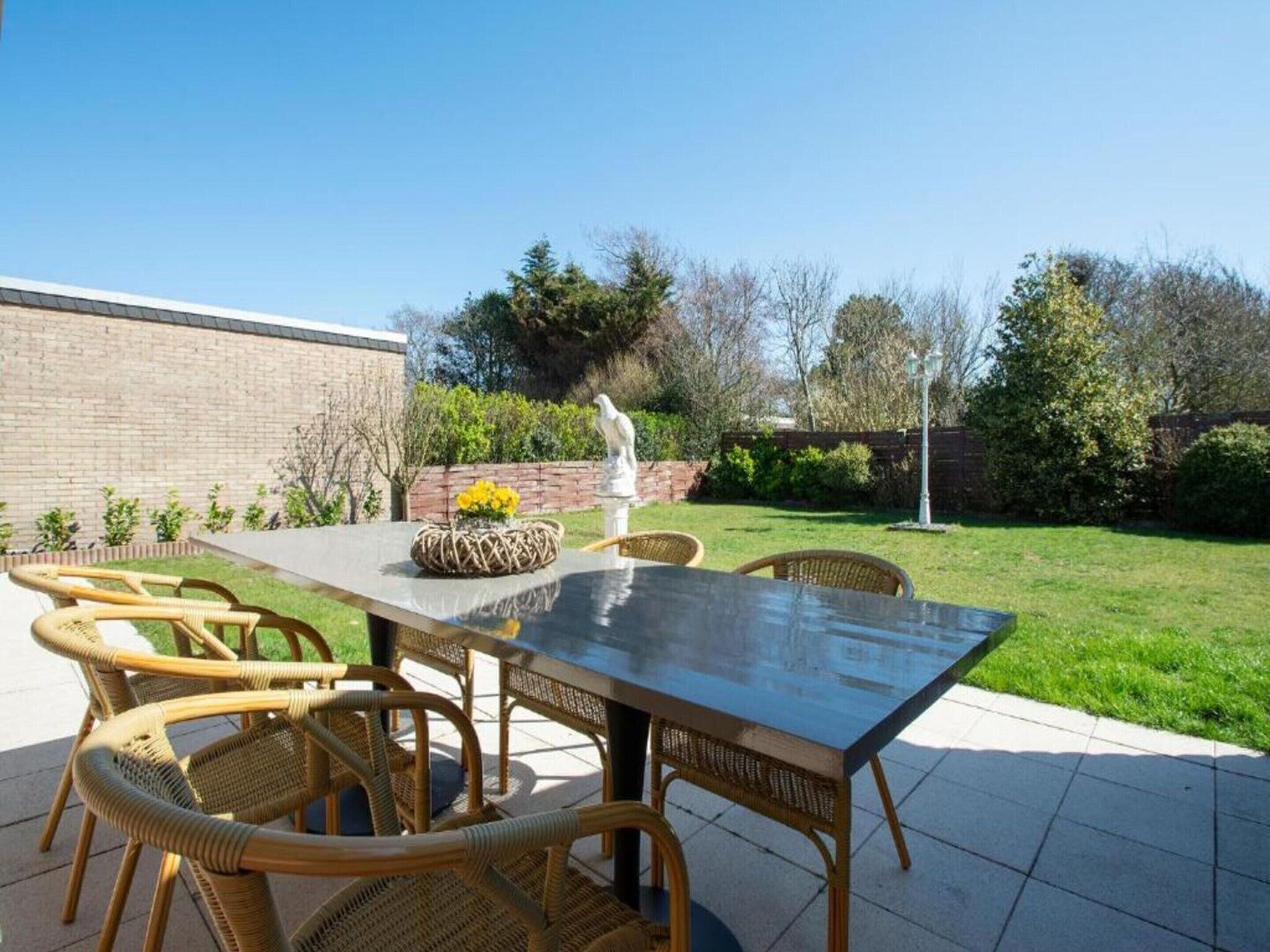 An outdoor patio with a rectangular table and wicker chairs.