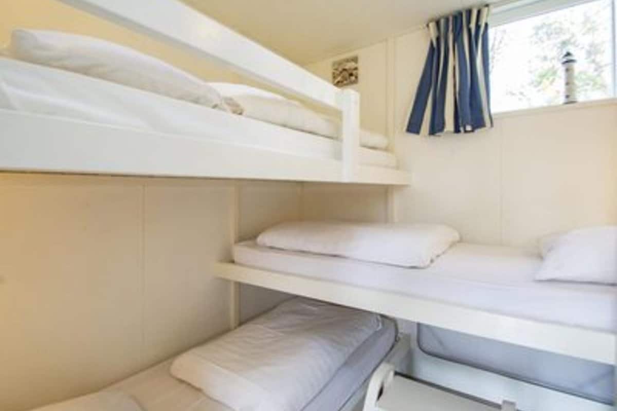 A bunk bed room with white bedding and a window with blue curtains.