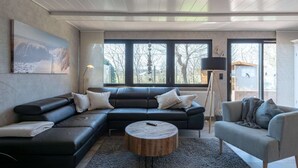 Una sala moderna con un sofá modular, una mesa de centro redonda y un sillón gris.