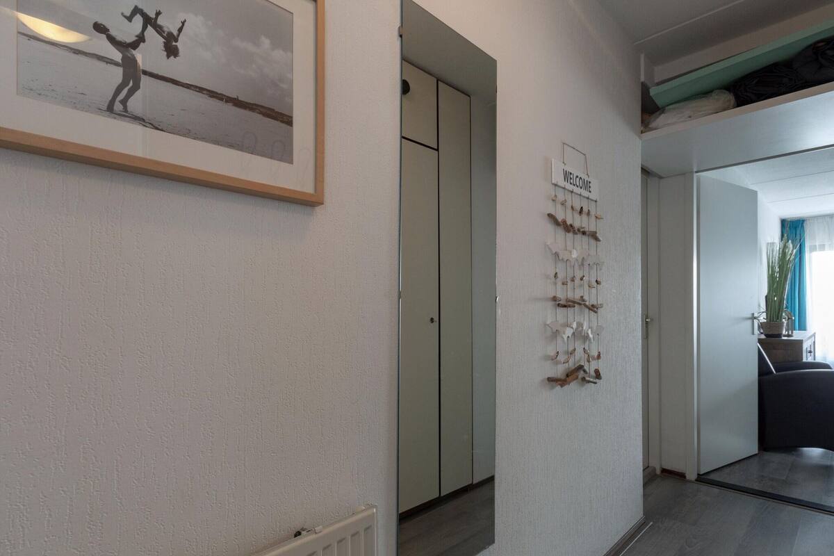 A hallway with a framed black and white photograph, a 'WELCOME' sign, and a wall-mounted decorative piece.