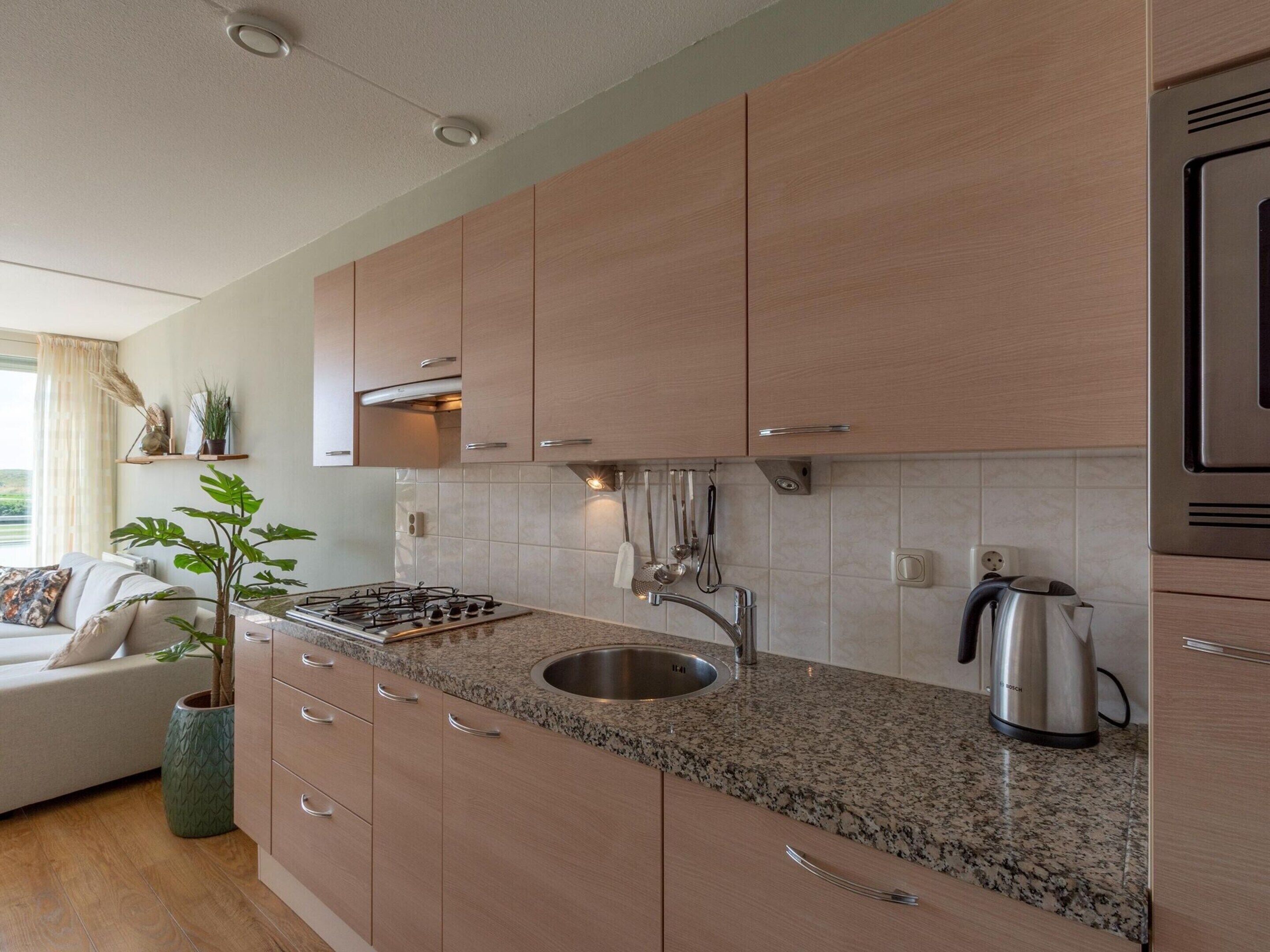 A modern kitchen with wooden cabinets, a granite countertop, stainless steel appliances, and a built-in sink.