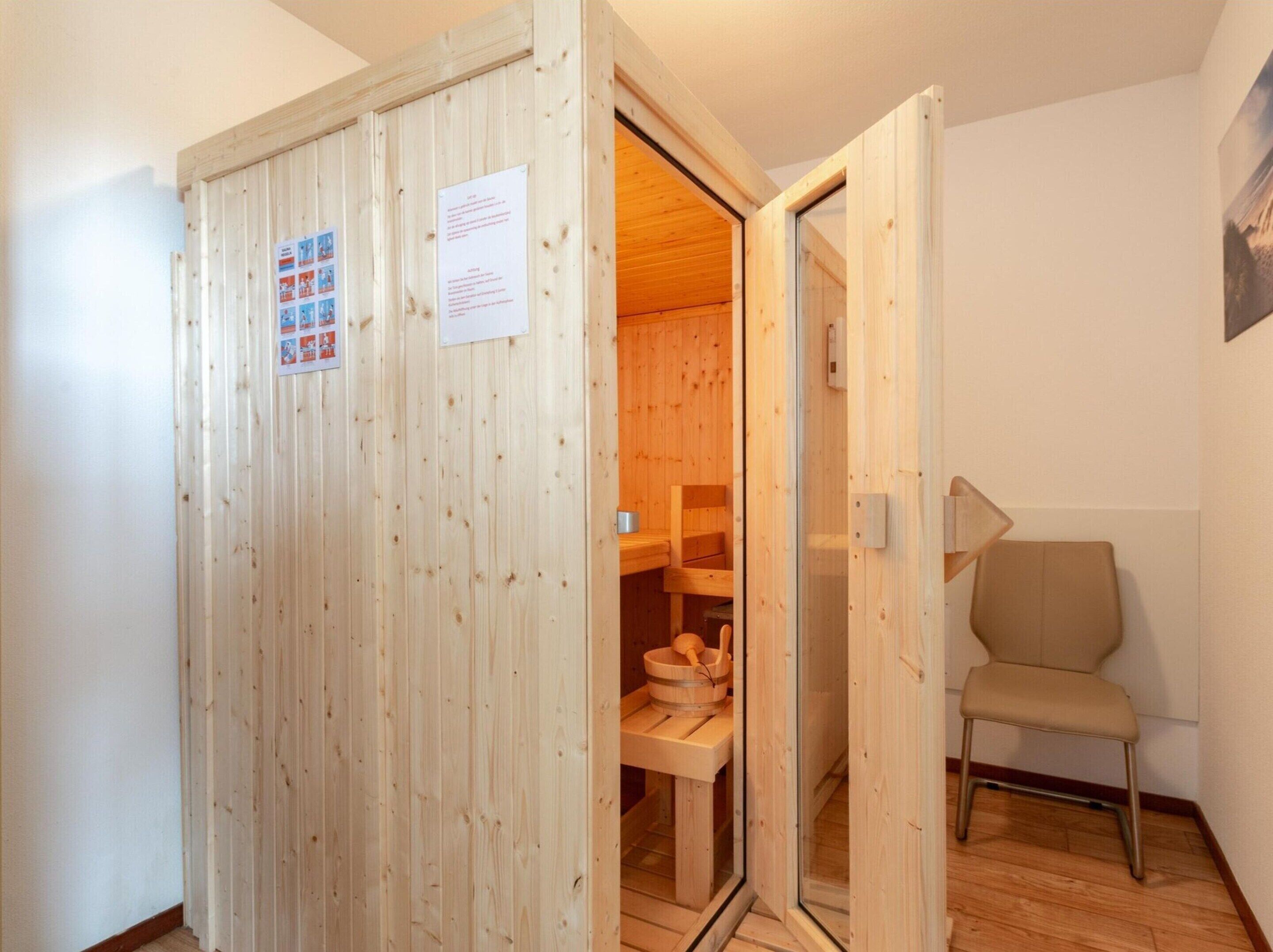 A wooden sauna room with a wooden bench and a bucket.