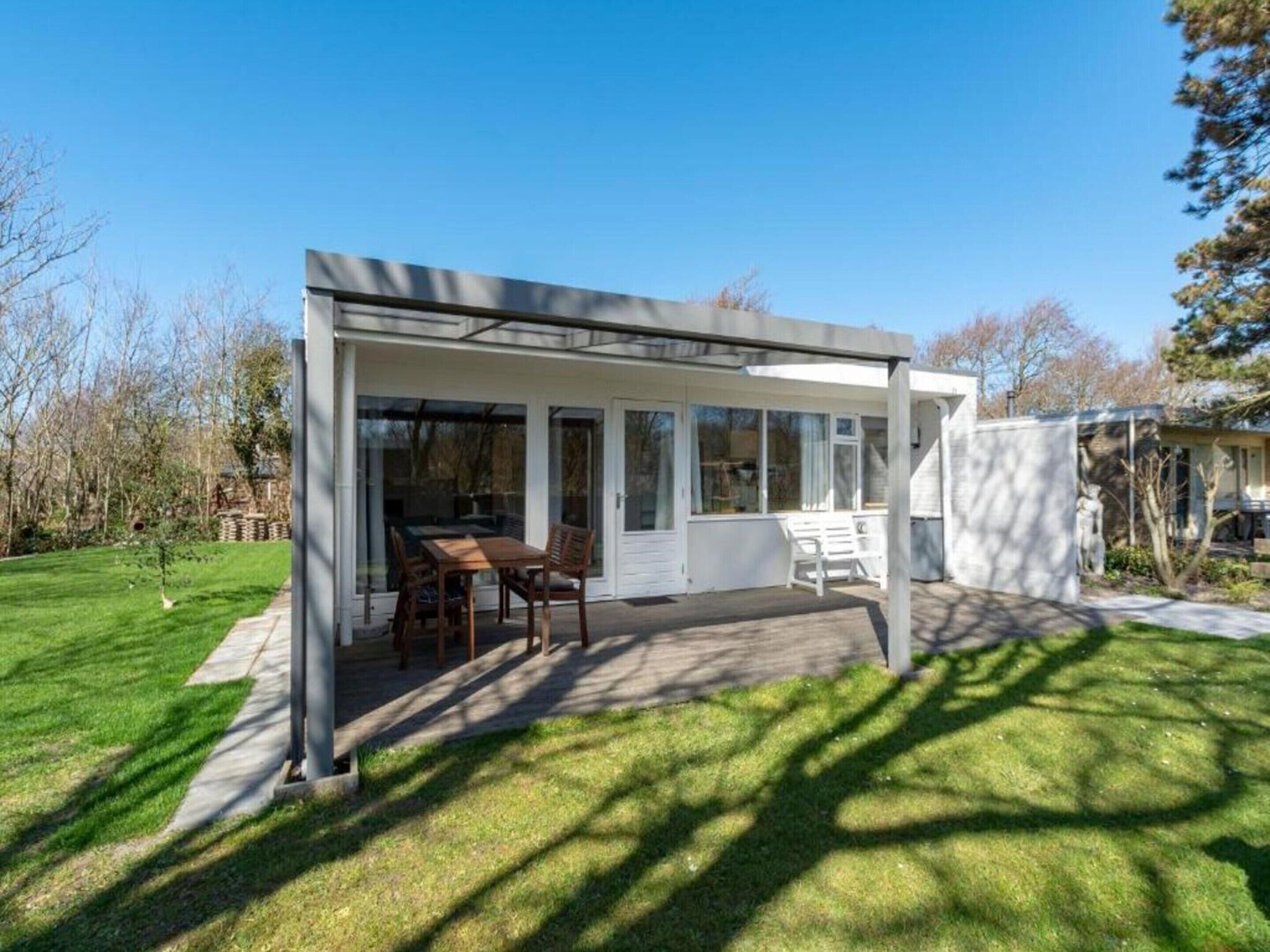 Une maison moderne dotée d’un patio couvert, d’un coin repas et d’une grande fenêtre.