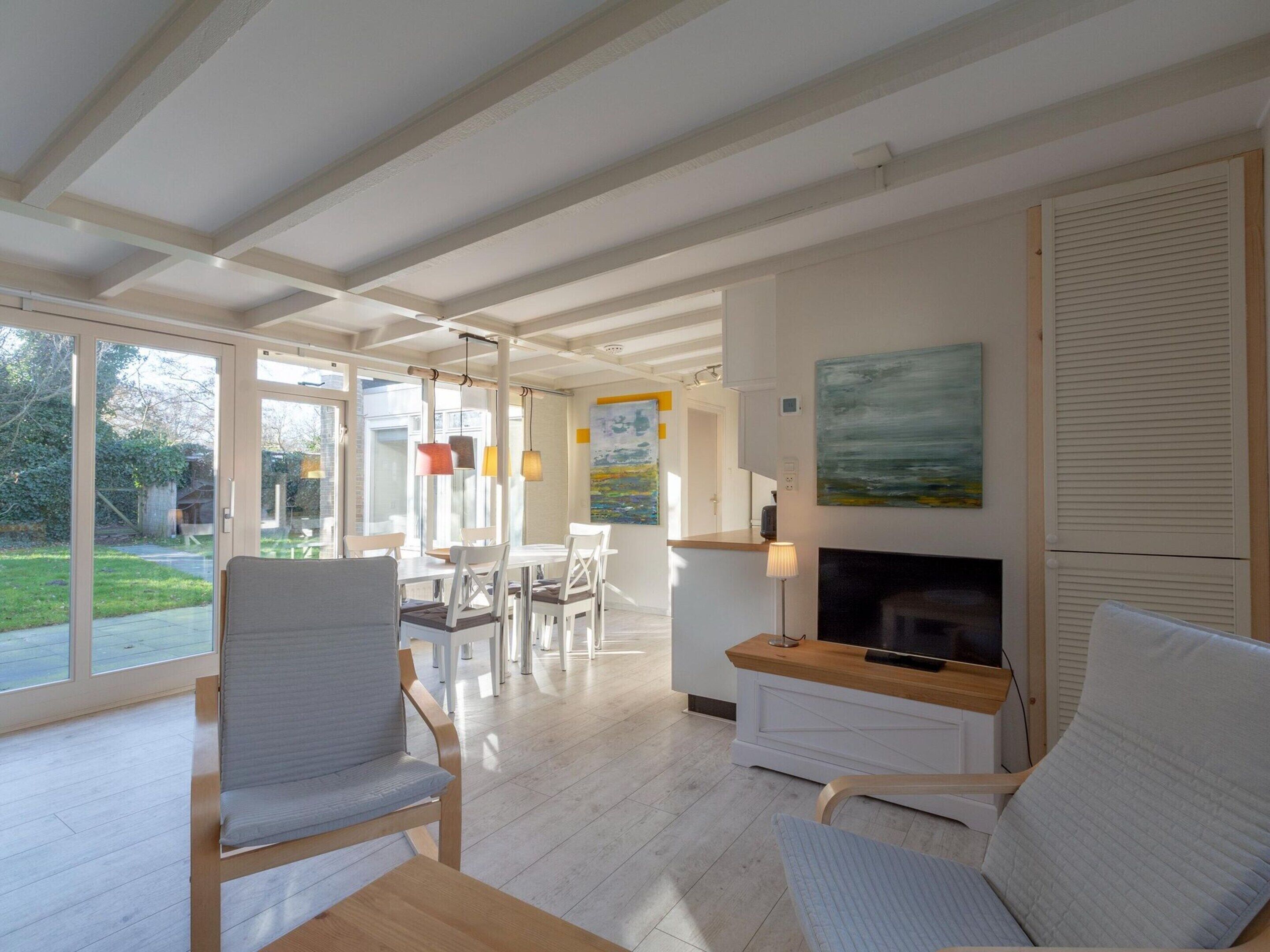 A spacious living room with a fireplace, a dining area, and a view of the garden.