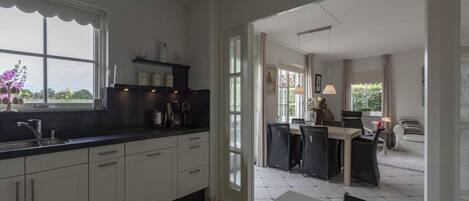 A modern kitchen with white cabinets, a black countertop, and a dining area with a table and chairs.