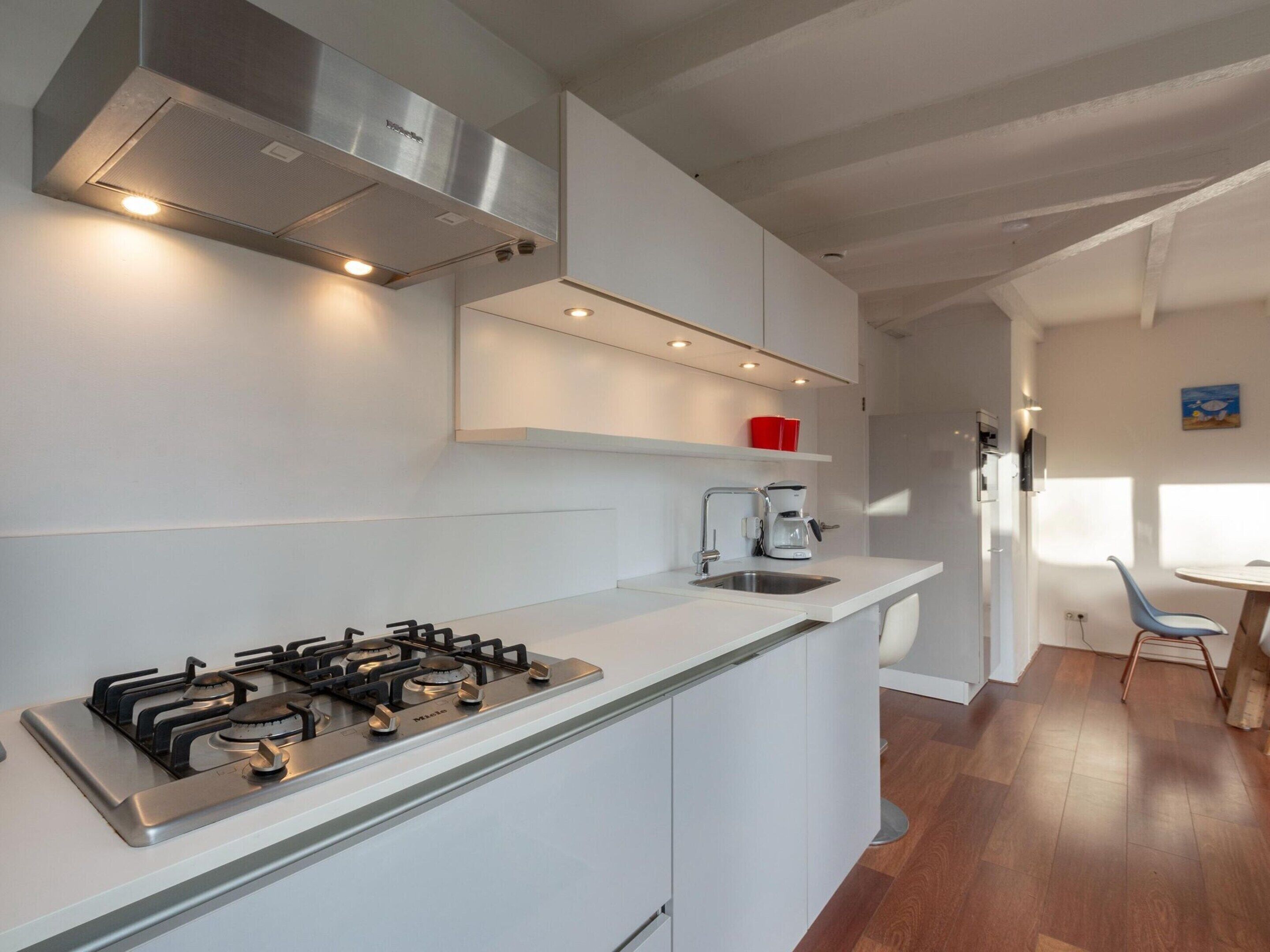 Une cuisine moderne équipée d’une cuisinière à gaz, d’une machine à café et d’un évier.