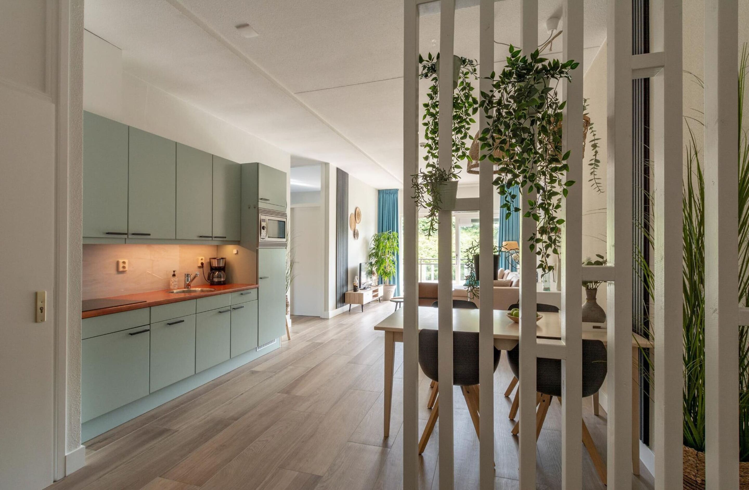 A modern kitchen with light green cabinets, a wooden countertop, and a built-in oven.
