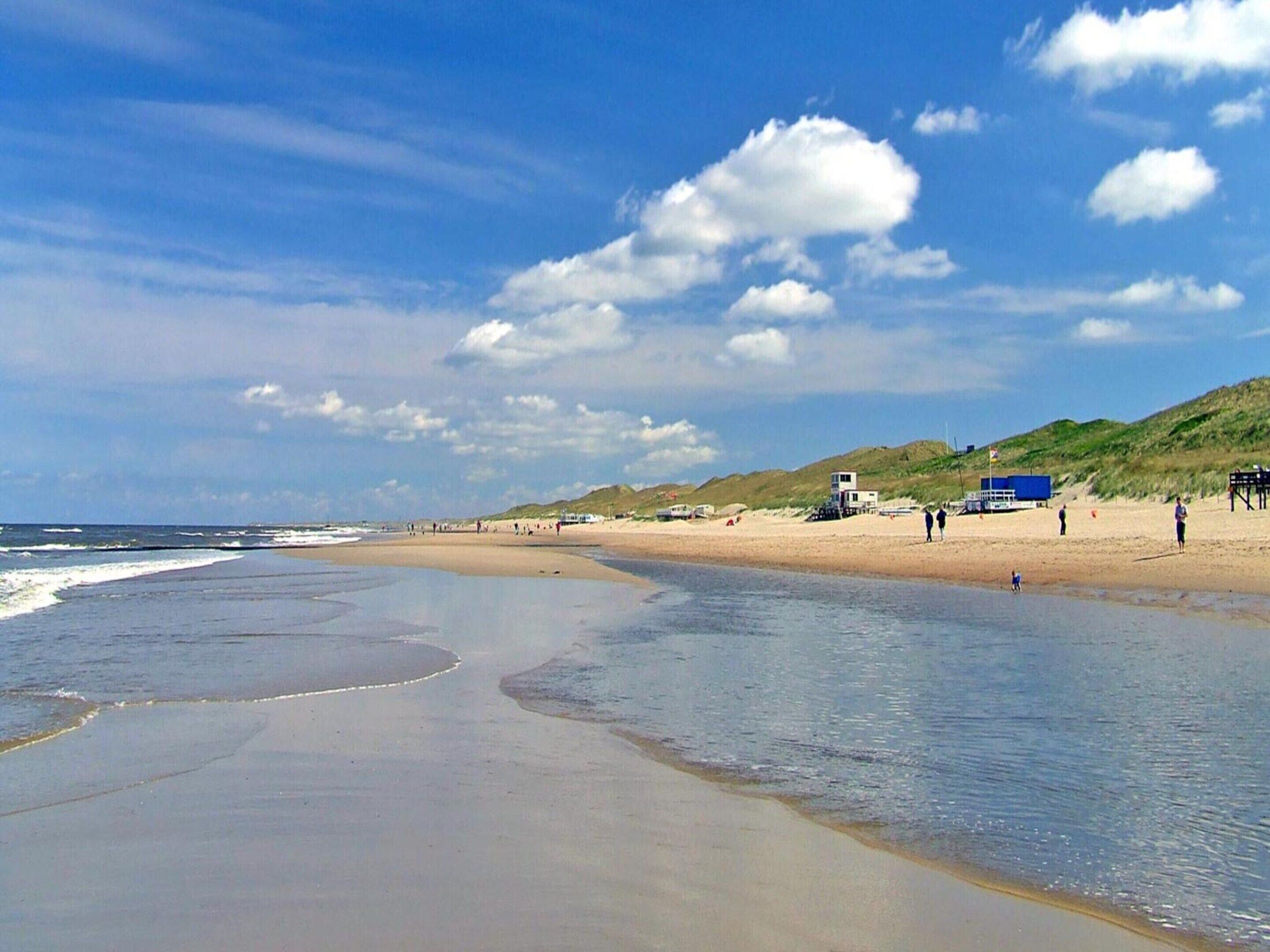 A beach with a sandy shore, a small water body, and a few people.