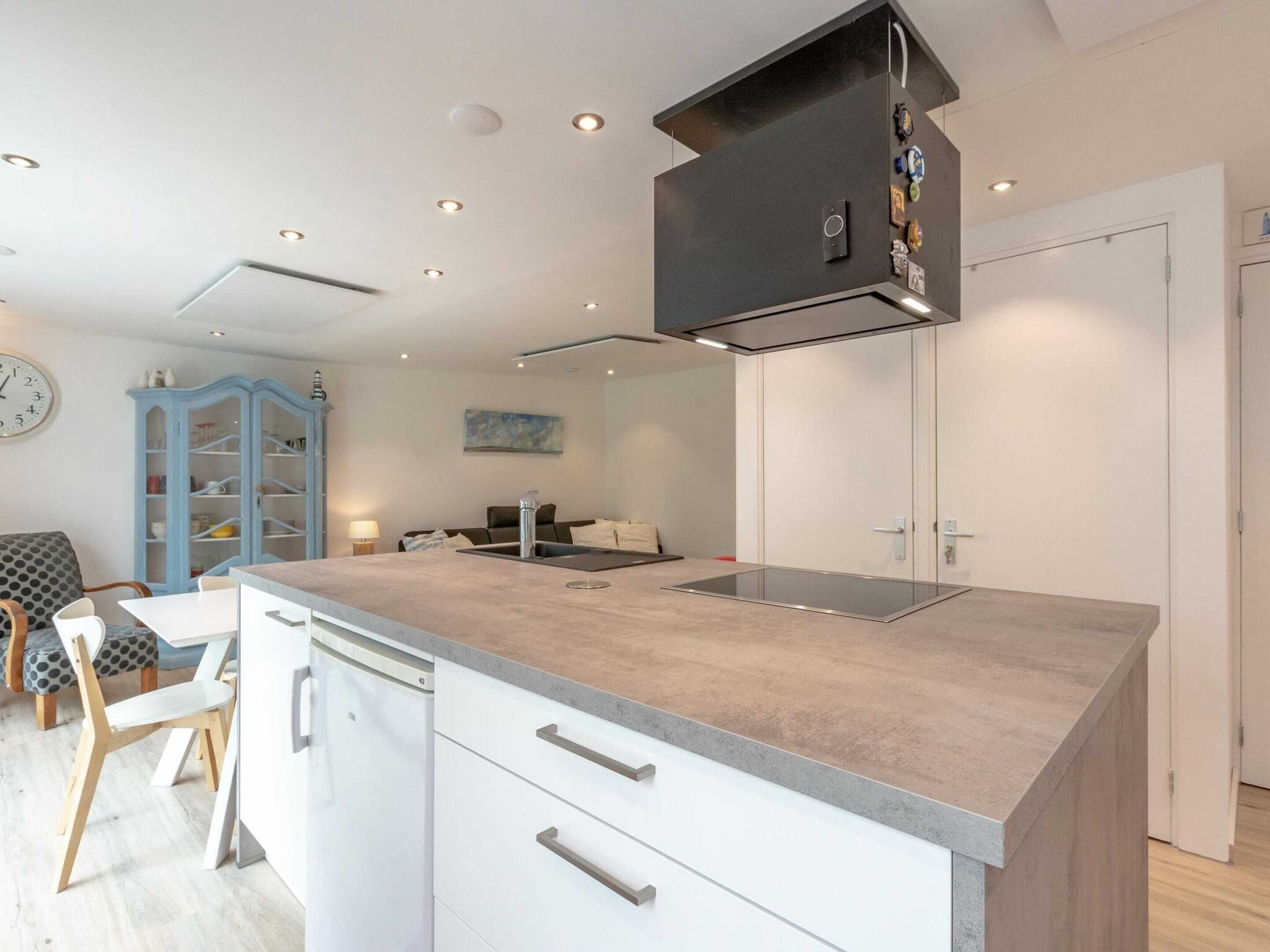 A modern kitchen with a central island, white cabinetry, and a built-in stove.