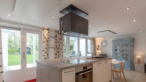 Uma cozinha moderna com ilha central, forno embutido e área de refeições com mesa e cadeiras.