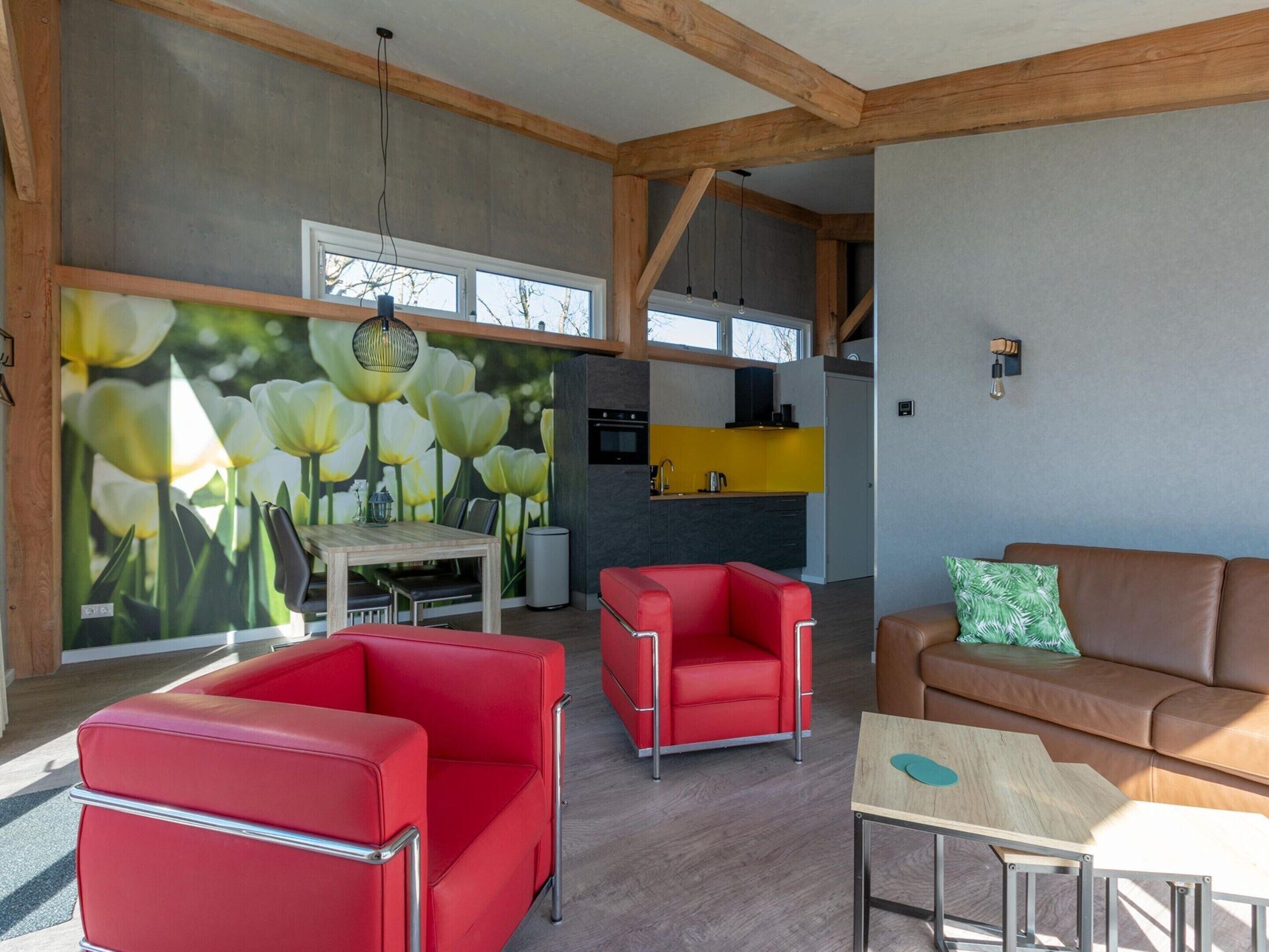 A modern living room with red and brown leather sofas, a wooden coffee table, and a dining area with a white table and chairs.