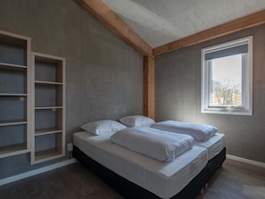 A bedroom with a bed, built-in shelving, and a window.