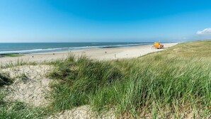 Ein Strand mit einer Düne und einem Rettungsturm.