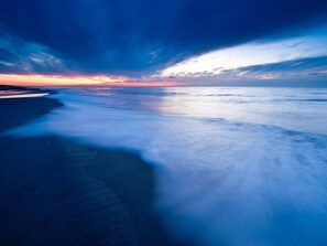 Une scène de plage avec un effet de longue exposition, capturant le mouvement des vagues et du ciel.