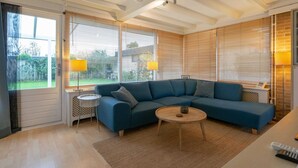 A modern living room with a sectional sofa, a round coffee table, and a small side table. - Comfortable Holiday Home in Sint Maartenszee (Sint Maartensvlotbrug)