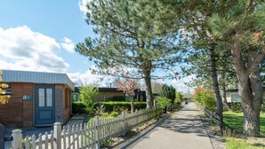 A residential street with a wooden fence, houses, and a clear sky. - Comfortable Holiday Home in Sint Maartenszee (Sint Maartensvlotbrug)