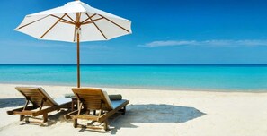 A beach with two wooden lounge chairs and a white umbrella. - Dream Home at Sarasota Gulf Estates Heated pool (Sarasota)