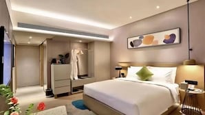 Una habitación de hotel moderna con una cama grande, mesitas de noche, una obra de arte colgada en la pared y un armario empotrado.
