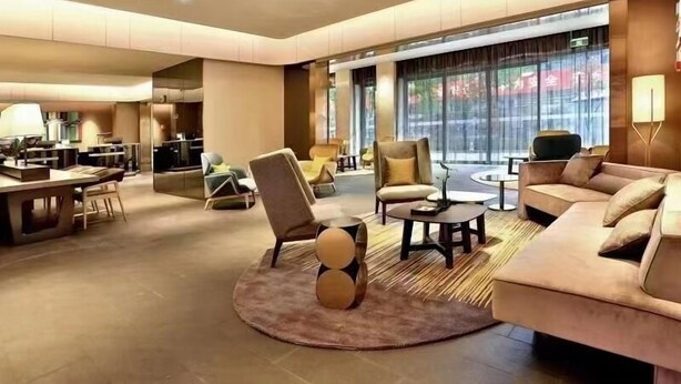 Un moderno vestíbulo de hotel con un área de descanso, un comedor y amplias ventanas.