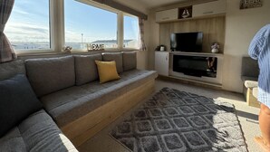 A modern living room with a grey sofa, a flat-screen TV, and a fireplace.
