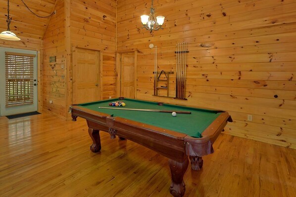 A pool table in a wooden room with a chandelier, a door with blinds, and a window. - New Listing! 2 Minutes from Pigeon Forge Parkway! Hot tub/Pool table/Romantic! (Pigeon Forge)