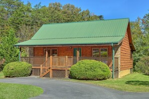 A wooden cabin with a green roof, a porch, and two well-maintained bushes. - New Listing! 2 Minutes from Pigeon Forge Parkway! Hot tub/Pool table/Romantic! (Pigeon Forge)