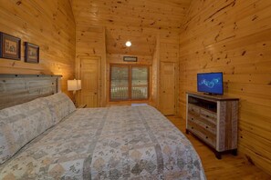 A wooden cabin room with a bed, a television, and a window with blinds. - New Listing! 2 Minutes from Pigeon Forge Parkway! Hot tub/Pool table/Romantic! (Pigeon Forge)