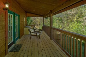 A wooden deck with a railing, two wicker chairs, and a small table. - New Listing! 2 Minutes from Pigeon Forge Parkway! Hot tub/Pool table/Romantic! (Pigeon Forge)