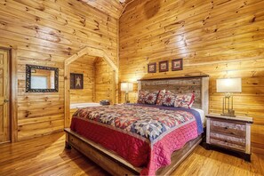 Un dormitorio con paneles de madera, una cama, dos lámparas de noche, una mesita de noche y un espejo.